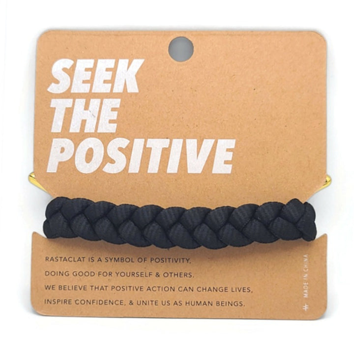 Rastaclat Men's Braided Bracelet on a tan display board that says seek the positive and company mottos with the back view of the braided black bracelet.