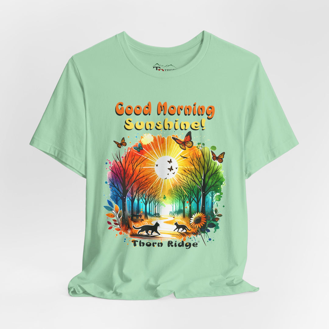 good morning sunshine graphic tee by Thorn Ridge featuring the sun shining through the trees and two cats walking across the path in a park.