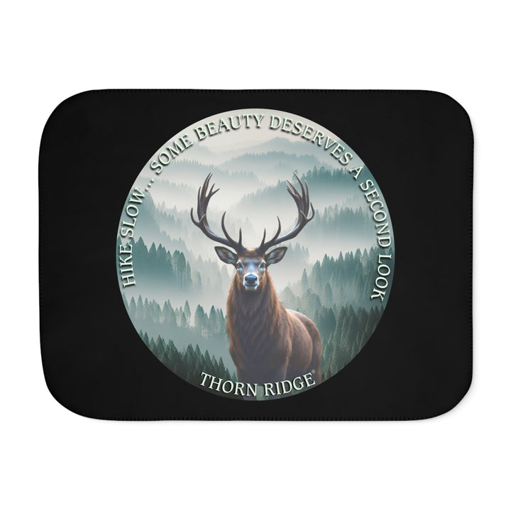 Hike Slow some beauty deserves a second look black sherpa blanket featuring a circular graphic of a buck looking at the camera with a green misty forest behind him and branded Thorn Ridge®