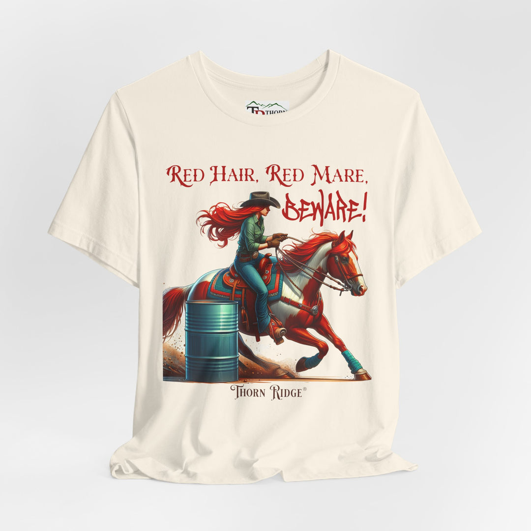 t-shirt with a graphic of a redhead woman on a horse barrel racing and the text 'Red Hair, Red Mare, Beware!' labeled Thorn Ridge®.