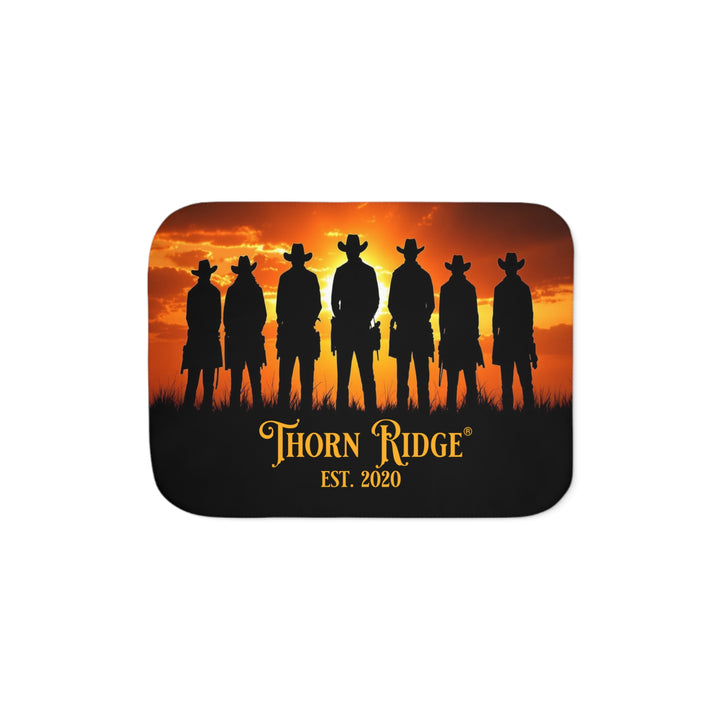 Silhouette of Seven Riders cowboys against an orange sunset with 'Thorn Ridge' branding on a sherpa blanket