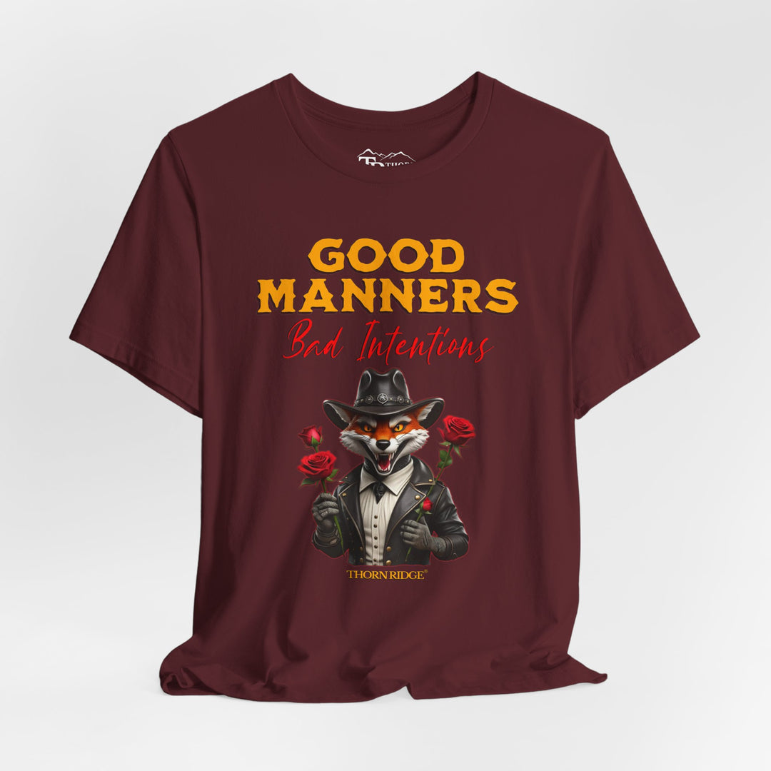 Good manners bad intentions graphic tee with a grinning fox wearing a black cowboy hat and leather jacket with human hands holding roses.  labeled Thorn Ridge®
