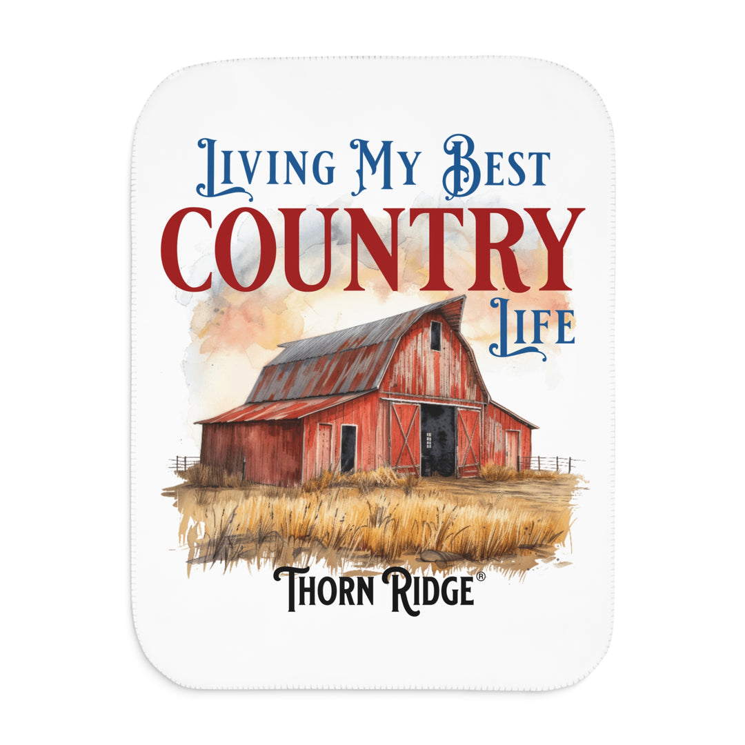 White Sherpa Blanket with a barn illustration and text 'Living My Best Country Life' by Thorn Ridge on a white background.