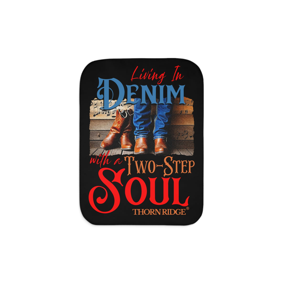 Black Sherpa blanket with text 'Living In Denim, with a Two-Step Soul by Thorn Ridge® and images of someone wearing jeans and boots from the shins down against a wooden wall with music notes on it and a empty pair of boots leaning against the man's leg.