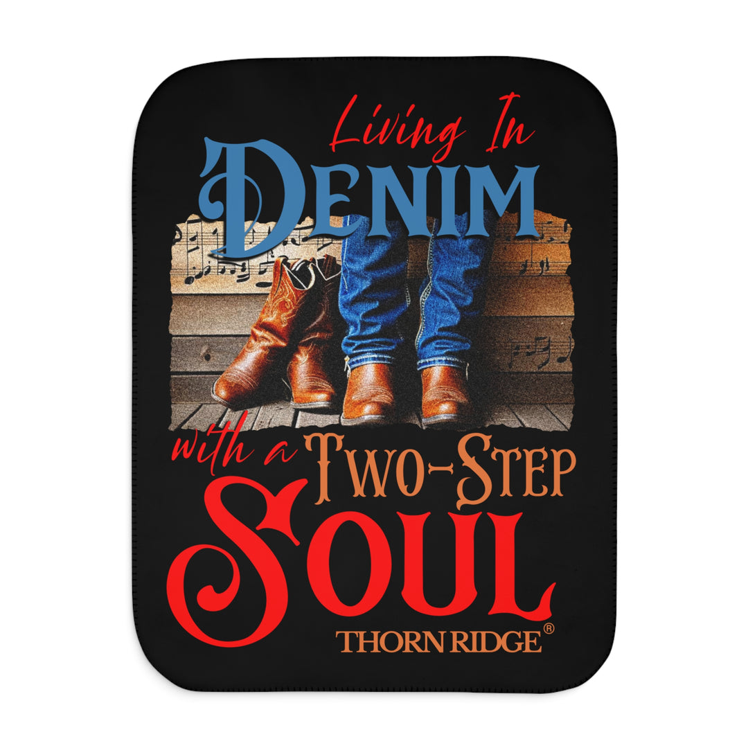Black Sherpa blanket with text 'Living In Denim, with a Two-Step Soul by Thorn Ridge® and images of someone wearing jeans and boots from the shins down against a wooden wall with music notes on it and a empty pair of boots leaning against the man's leg.