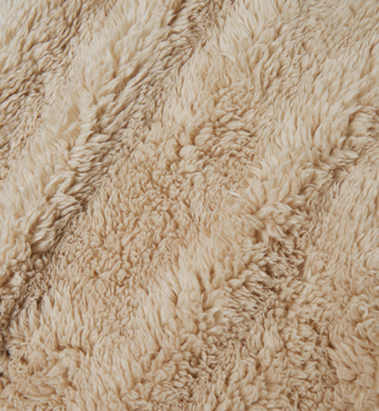 Close-up of beige, fluffy sherpa 
fabric texture