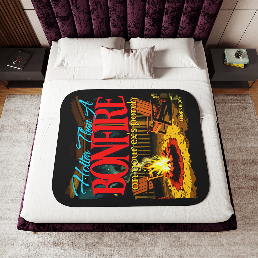 Hotter than a bonfire on your ex's porch slogan by Thorn Ridge® on a black sherpa blanket with the image of a bonfire on a porch.