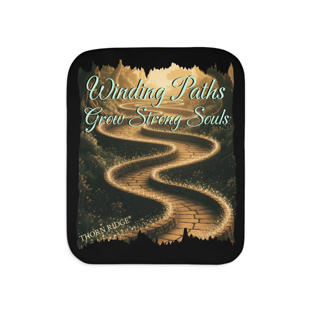 Winding Paths Grow Strong Souls black sherpa blanket with an image of a winding golden brick path through a forest with lights on top of the bricks that edge the path. By Thorn Ridge®