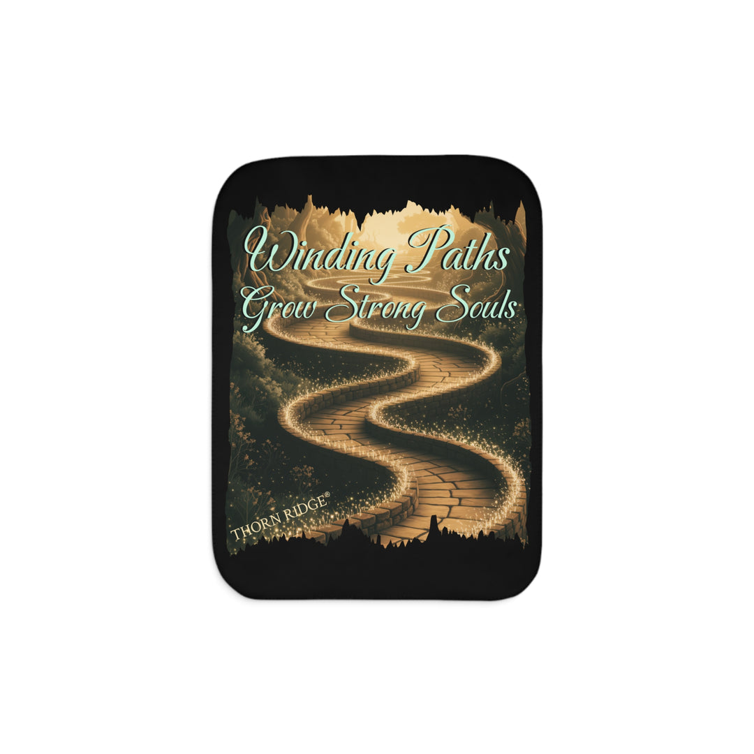 Winding Paths Grow Strong Souls black sherpa blanket with an image of a winding golden brick path through a forest with lights on top of the bricks that edge the path. By Thorn Ridge®