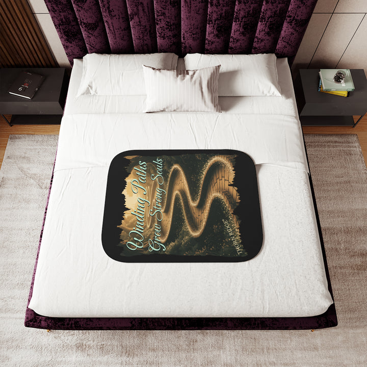 Winding Paths Grow Strong Souls black sherpa blanket with an image of a winding golden brick path through a forest with lights on top of the bricks that edge the path. By Thorn Ridge®