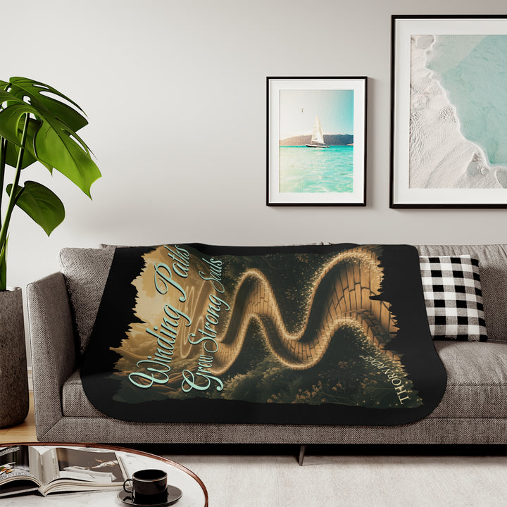 Winding Paths Grow Strong Souls black sherpa blanket with an image of a winding golden brick path through a forest with lights on top of the bricks that edge the path. By Thorn Ridge®