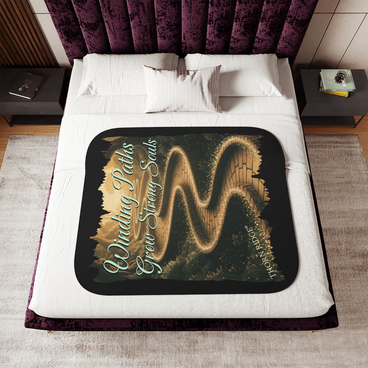 Winding Paths Grow Strong Souls black sherpa blanket with an image of a winding golden brick path through a forest with lights on top of the bricks that edge the path. By Thorn Ridge®