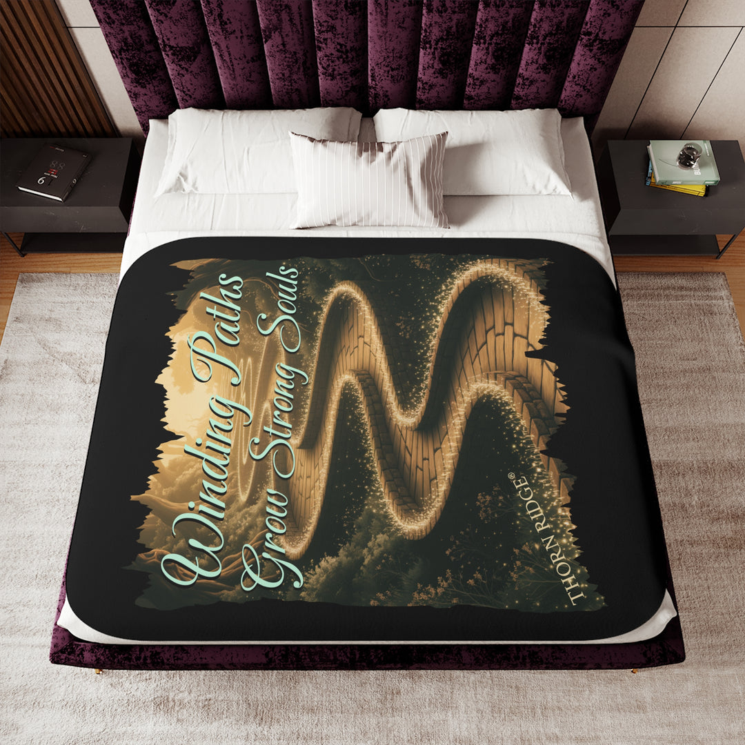 Winding Paths Grow Strong Souls black sherpa blanket with an image of a winding golden brick path through a forest with lights on top of the bricks that edge the path. By Thorn Ridge®