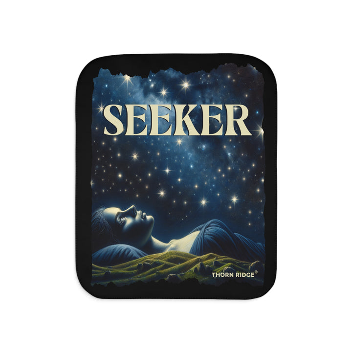 Seeker sherpa blanket in blacks and blues featuring the night sky and a woman laying on the ground stargazing. Branded Thorn Ridge®