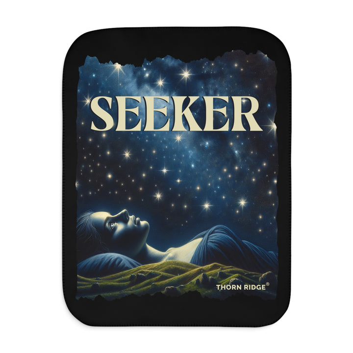 Seeker sherpa blanket in blacks and blues featuring the night sky and a woman laying on the ground stargazing. Branded Thorn Ridge®