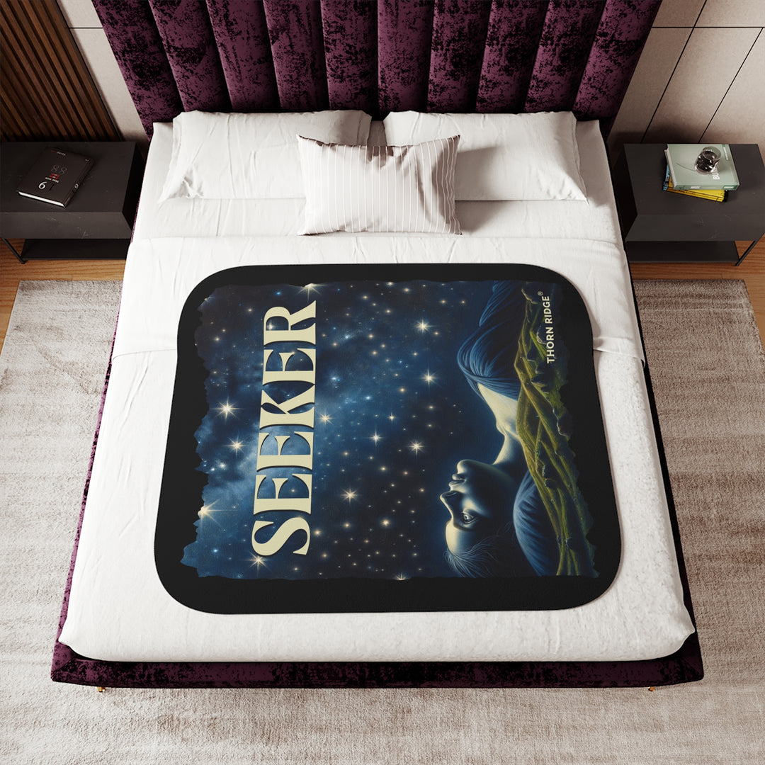 Seeker sherpa blanket in blacks and blues featuring the night sky and a woman laying on the ground stargazing. Branded Thorn Ridge®