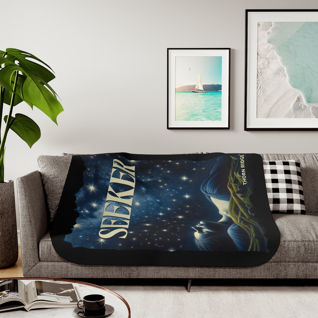 Seeker sherpa blanket in blacks and blues featuring the night sky and a woman laying on the ground stargazing. Branded Thorn Ridge®