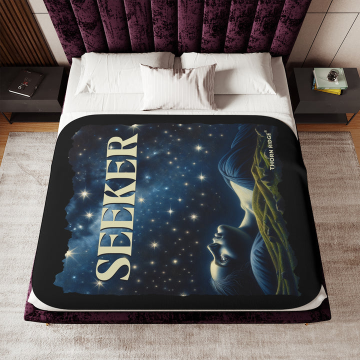Seeker sherpa blanket in blacks and blues featuring the night sky and a woman laying on the ground stargazing. Branded Thorn Ridge®