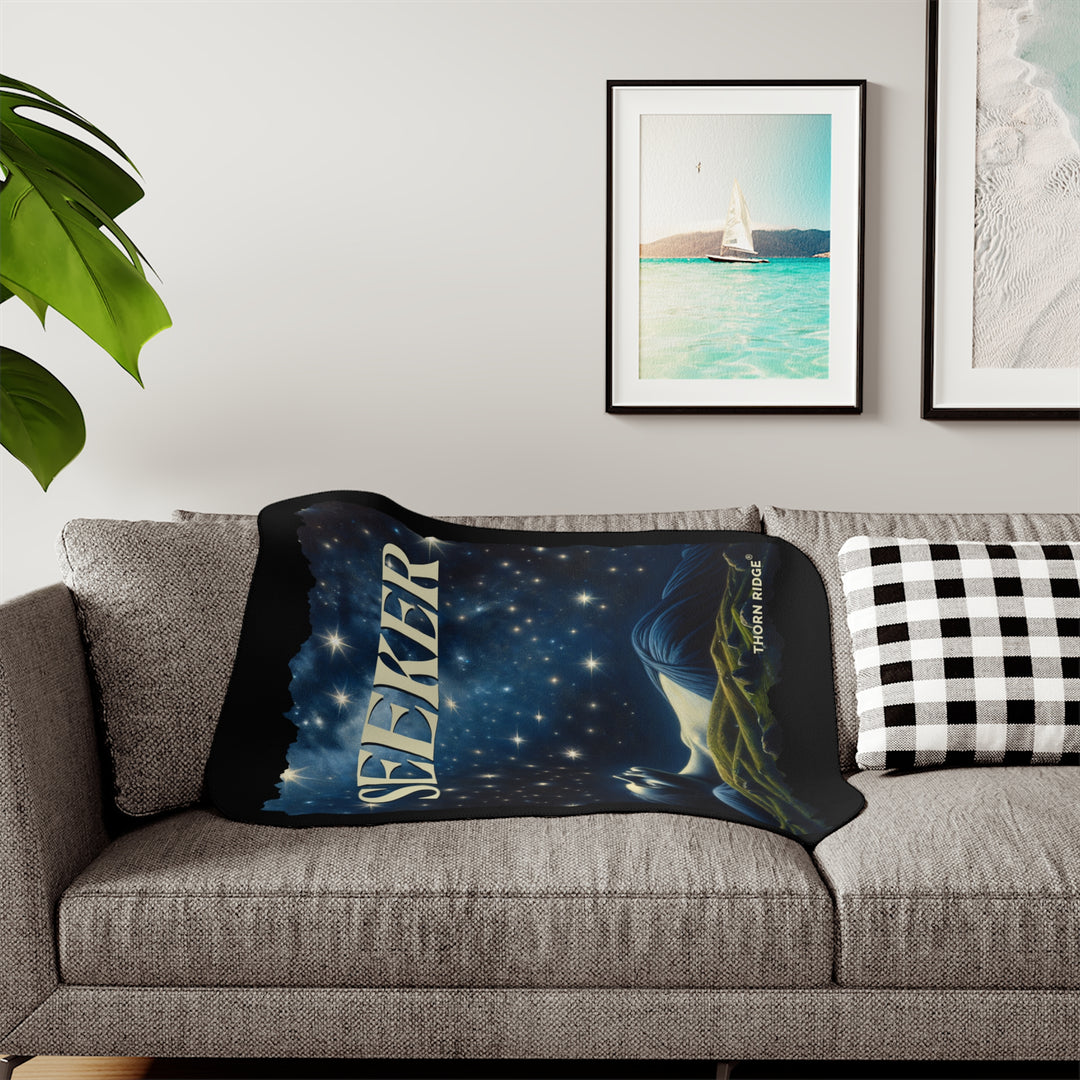 Seeker sherpa blanket in blacks and blues featuring the night sky and a woman laying on the ground stargazing. Branded Thorn Ridge®