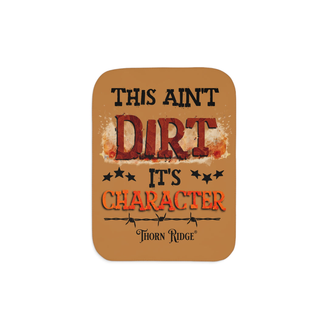This ain't dirt, it's character slogan by Thorn Ridge® on a light brown sherpa blanket.