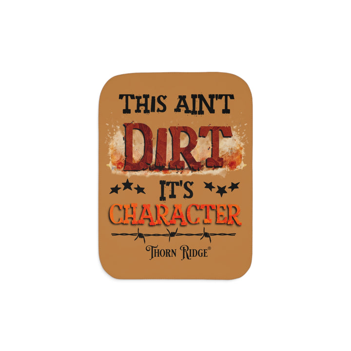 This ain't dirt, it's character slogan by Thorn Ridge® on a light brown sherpa blanket.