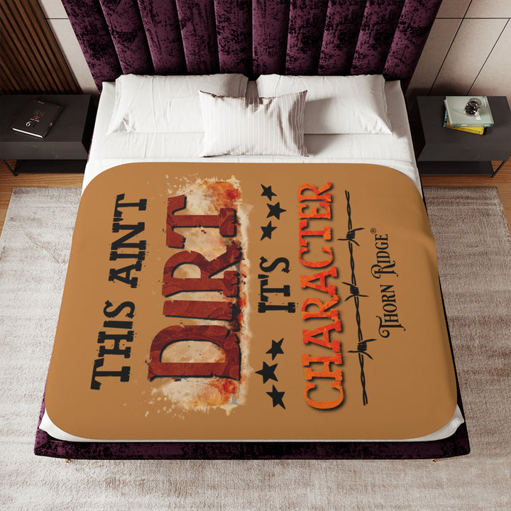This ain't dirt, it's character slogan by Thorn Ridge® on a light brown sherpa blanket.