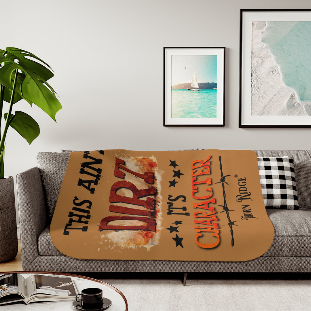 This ain't dirt, it's character slogan by Thorn Ridge® on a light brown sherpa blanket.