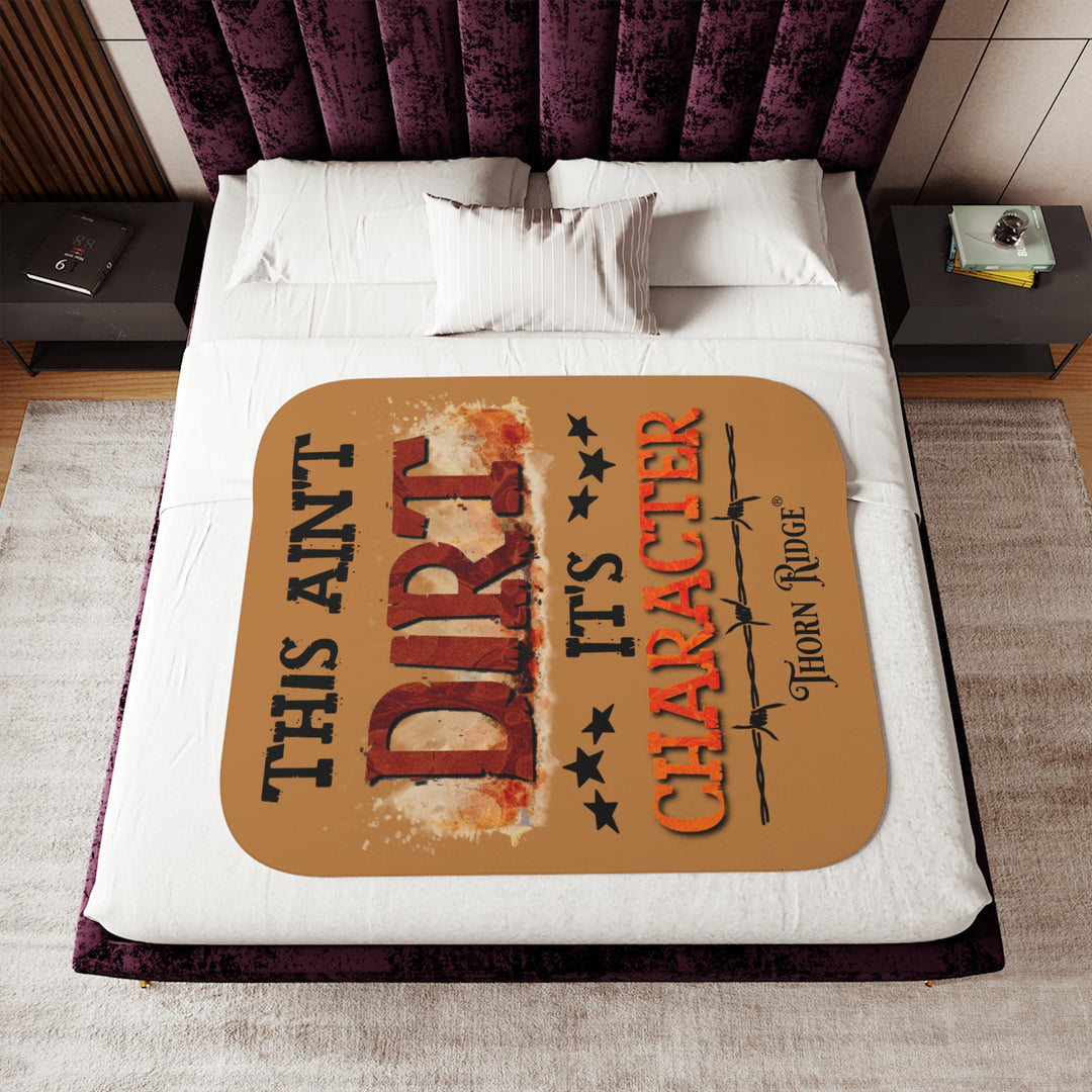 This ain't dirt, it's character slogan by Thorn Ridge® on a light brown sherpa blanket.