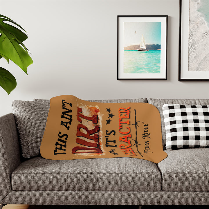 This ain't dirt, it's character slogan by Thorn Ridge® on a light brown sherpa blanket.