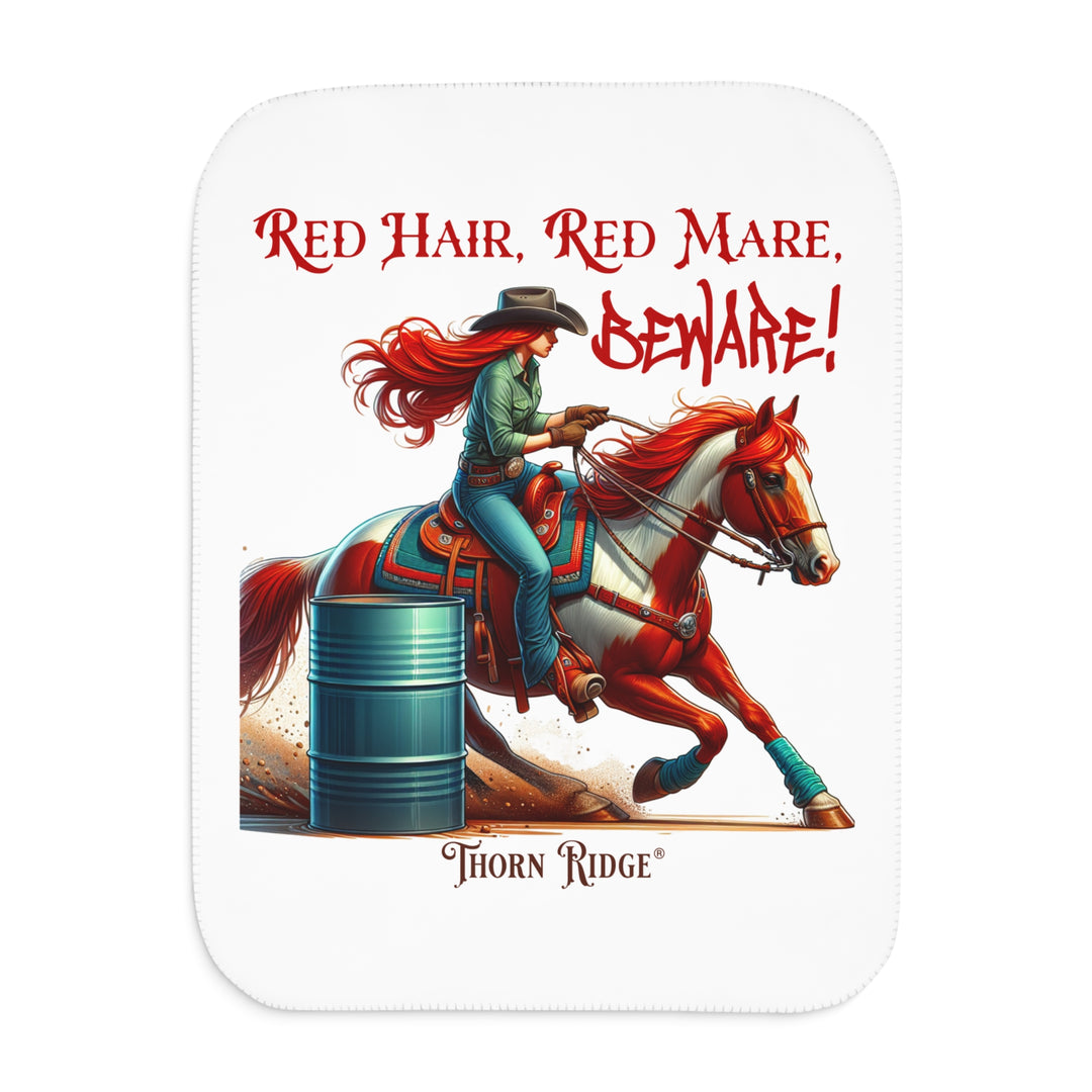 white sherpa blanket with a graphic of a redheaded woman on a tobiano  chestnut horse racing around a barrel and text 'Red Hair, Red Mare, Beware!' by Thorn Ridge®.