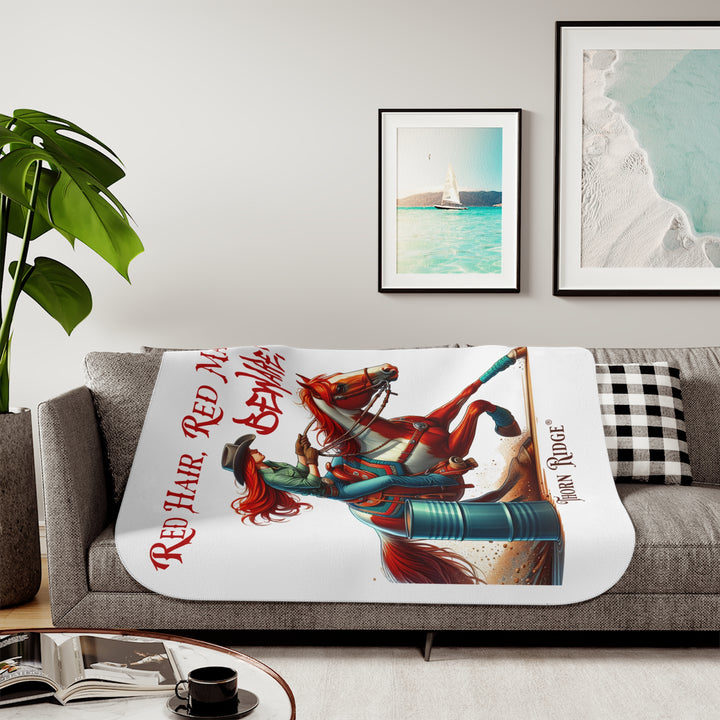 white sherpa blanket with a graphic of a redheaded woman on a tobiano  chestnut horse racing around a barrel and text 'Red Hair, Red Mare, Beware!' by Thorn Ridge®.