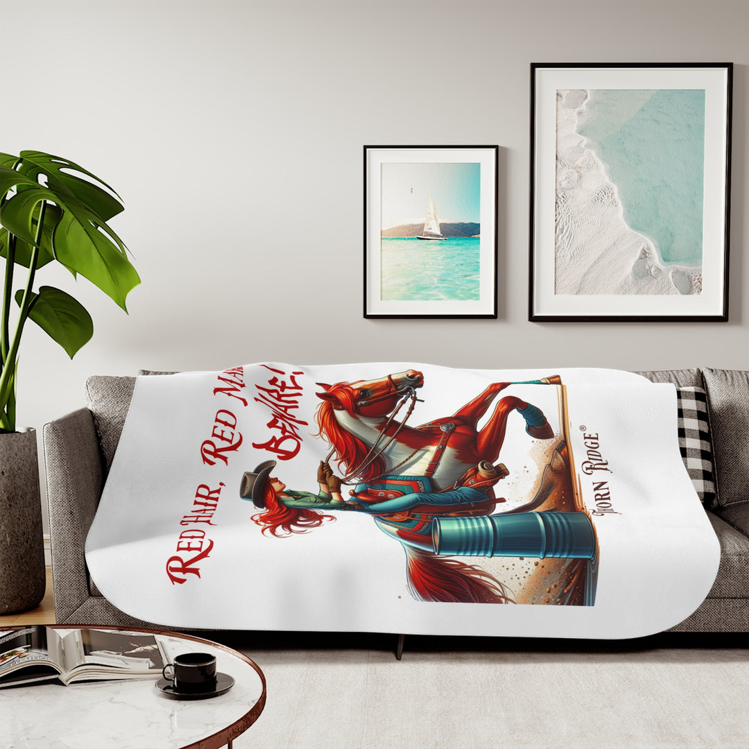 white sherpa blanket with a graphic of a redheaded woman on a tobiano  chestnut horse racing around a barrel and text 'Red Hair, Red Mare, Beware!' by Thorn Ridge®.