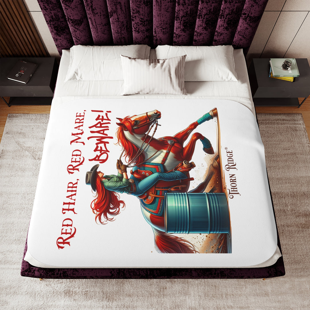 white sherpa blanket with a graphic of a redheaded woman on a tobiano  chestnut horse racing around a barrel and text 'Red Hair, Red Mare, Beware!' by Thorn Ridge®.