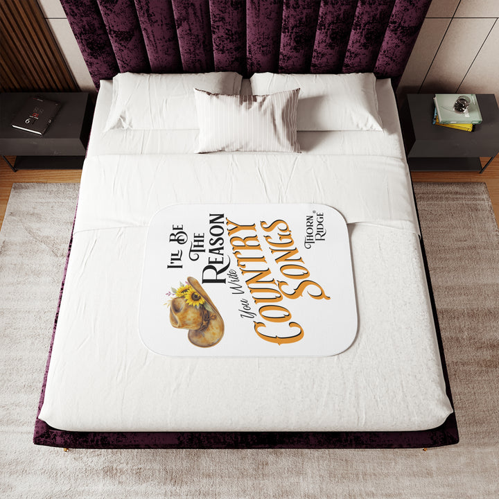 Decorative white sherpa blanket with a yellow sunflower cowgirl hat, sunflower, and text 'I'll be the reason you write country songs' by Thorn Ridge®