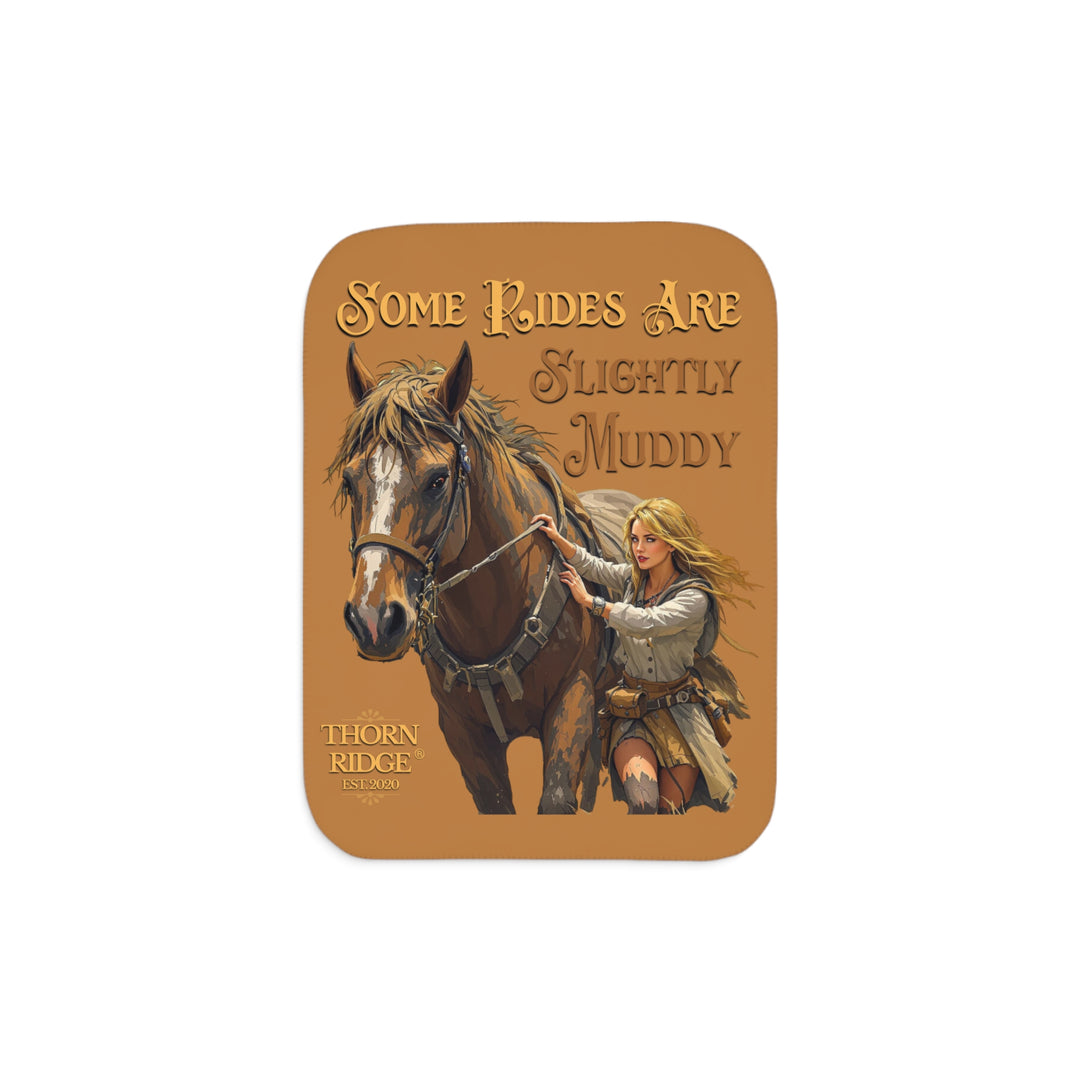 Some Rides Are Slightly Muddy tan sherpa blanket with an illustration of a draft horse in tack and a blond woman walking beside it both covered in mud and branded Thorn Ridge® EST 2020.