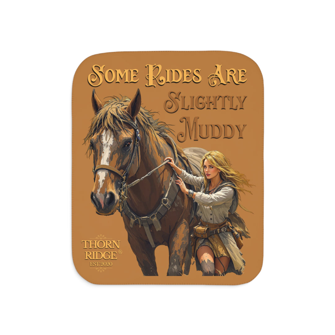 Some Rides Are Slightly Muddy tan sherpa blanket with an illustration of a draft horse in tack and a blond woman walking beside it both covered in mud and branded Thorn Ridge® EST 2020.