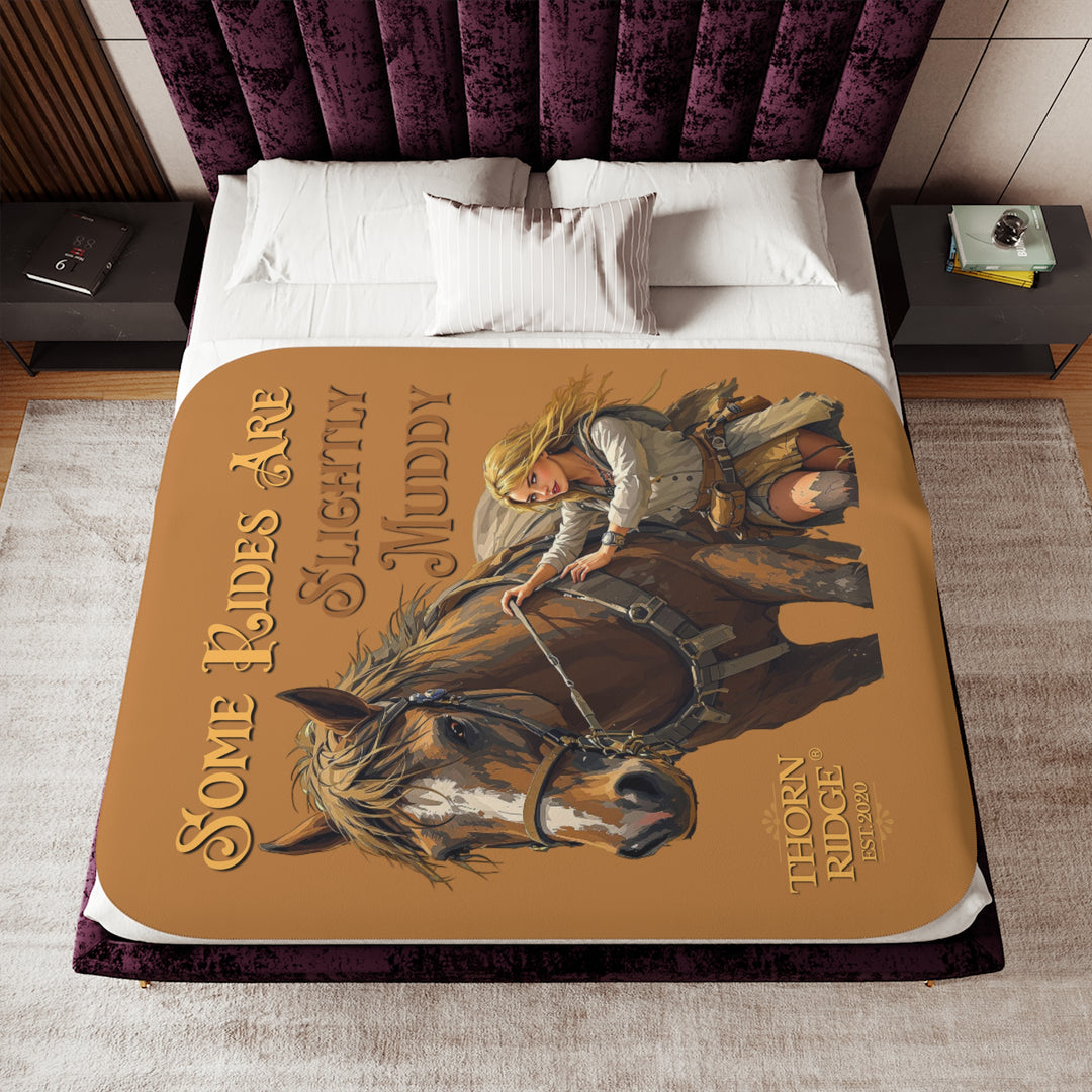 Some Rides Are Slightly Muddy tan sherpa blanket with an illustration of a draft horse in tack and a blond woman walking beside it both covered in mud and branded Thorn Ridge® EST 2020.
