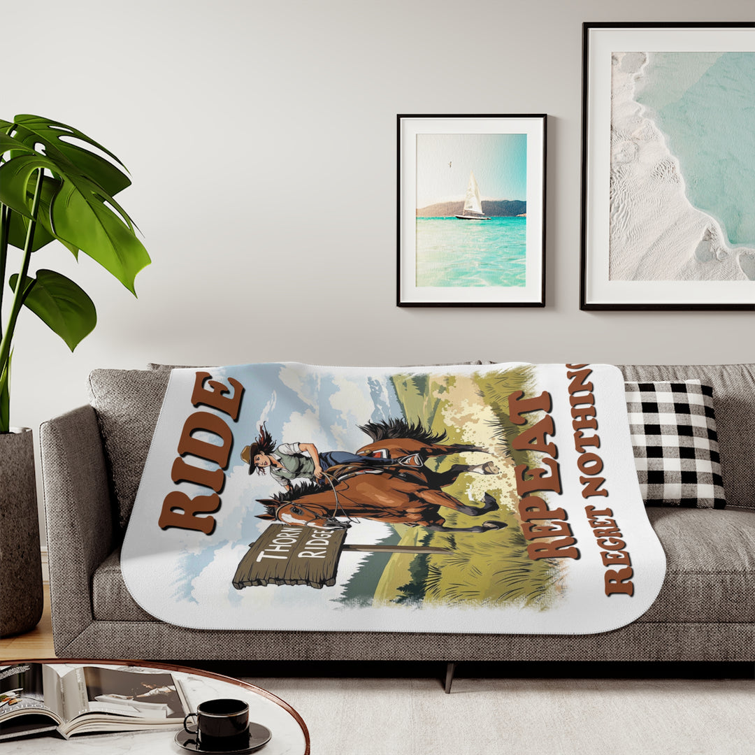 Decorative white sherpa blanket with a horse and rider graphic and text 'Ride Repeat Regret Nothing' and a sign that says the brand name Thorn Ridge®.