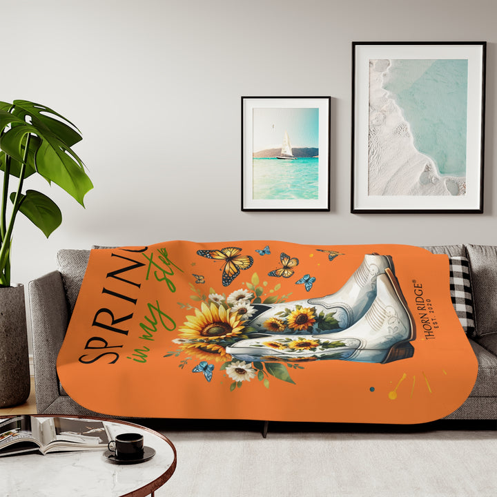 Spring in My Step Orange sherpa blanket with white cowgirl boots filled with sunflowers and sunflower decorations on the boots and butterflys around the boots by Thorn Ridge® Est 2020.