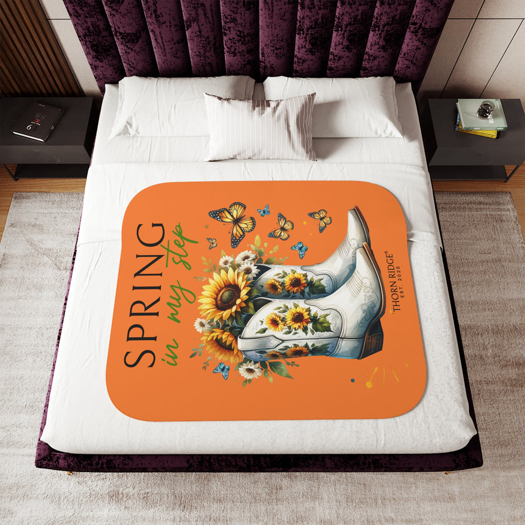 Spring in My Step Orange sherpa blanket with white cowgirl boots filled with sunflowers and sunflower decorations on the boots and butterflys around the boots by Thorn Ridge® Est 2020.
