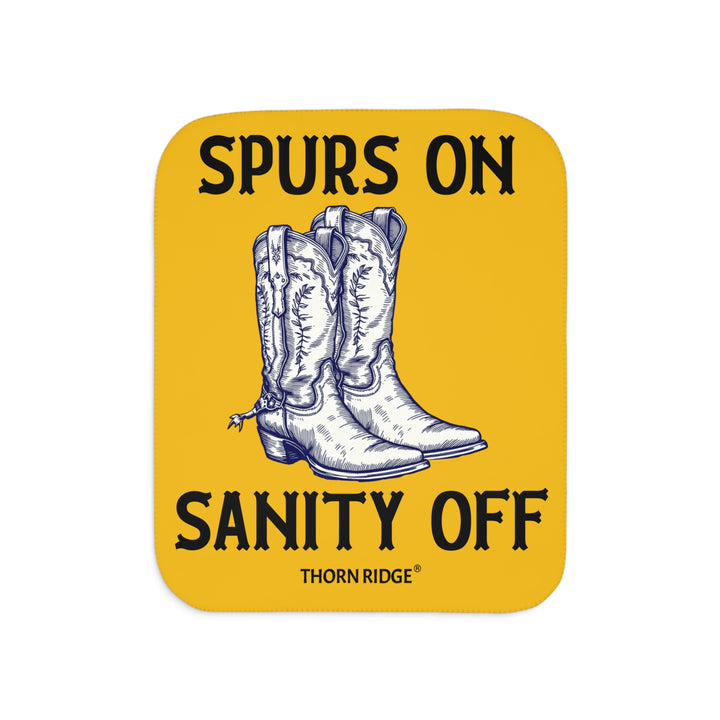 Spurs On Sanity Off yellow sherpa blanket with an illustration of white cowboy boots with spurs in the middle and branding Thorn Ridge®