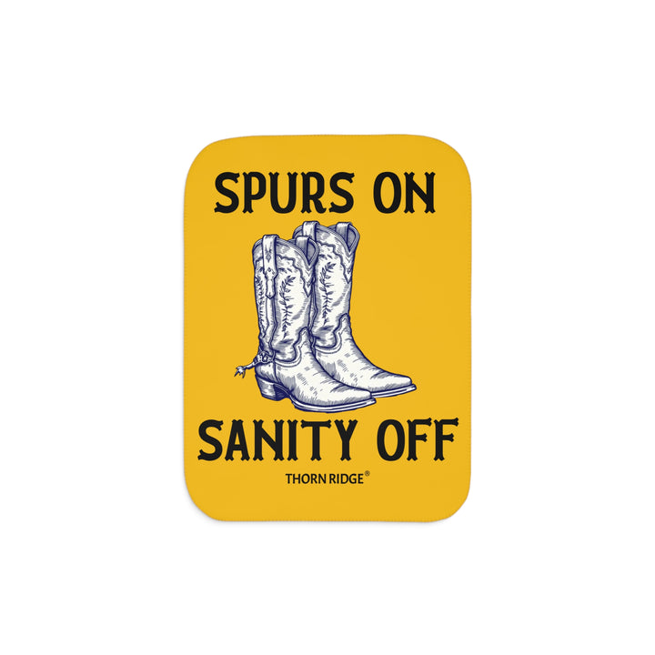 Spurs On Sanity Off yellow sherpa blanket with an illustration of white cowboy boots with spurs in the middle and branding Thorn Ridge®