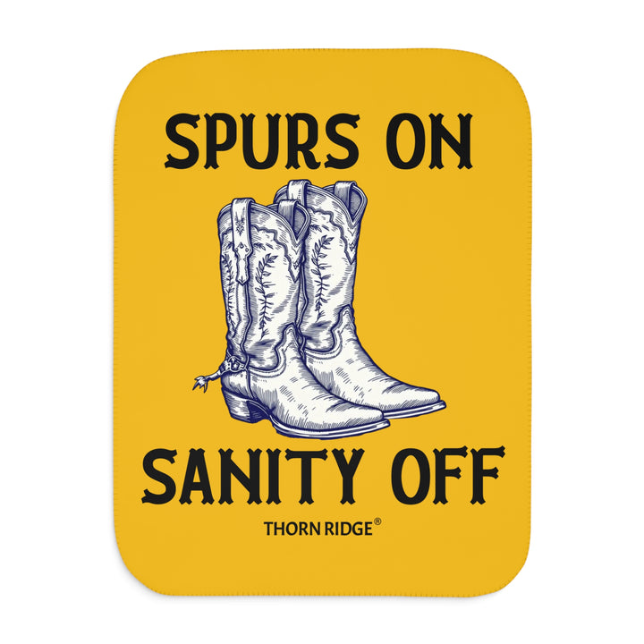Spurs On Sanity Off yellow sherpa blanket with an illustration of white cowboy boots with spurs in the middle and branding Thorn Ridge®