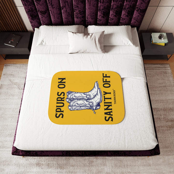 Spurs On Sanity Off yellow sherpa blanket with an illustration of white cowboy boots with spurs in the middle and branding Thorn Ridge®