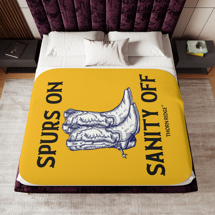 Spurs On Sanity Off yellow sherpa blanket with an illustration of white cowboy boots with spurs in the middle and branding Thorn Ridge®