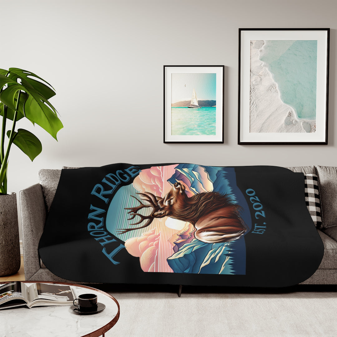 Black sherpa blanket with an illustration of a buck with antlers looking to the right with images of mountains in the background and the text Thorn Ridge® Est. 2020