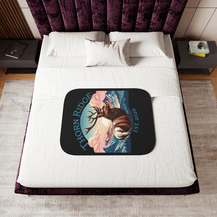 Black sherpa blanket with an illustration of a buck with antlers looking to the right with images of mountains in the background and the text Thorn Ridge® Est. 2020