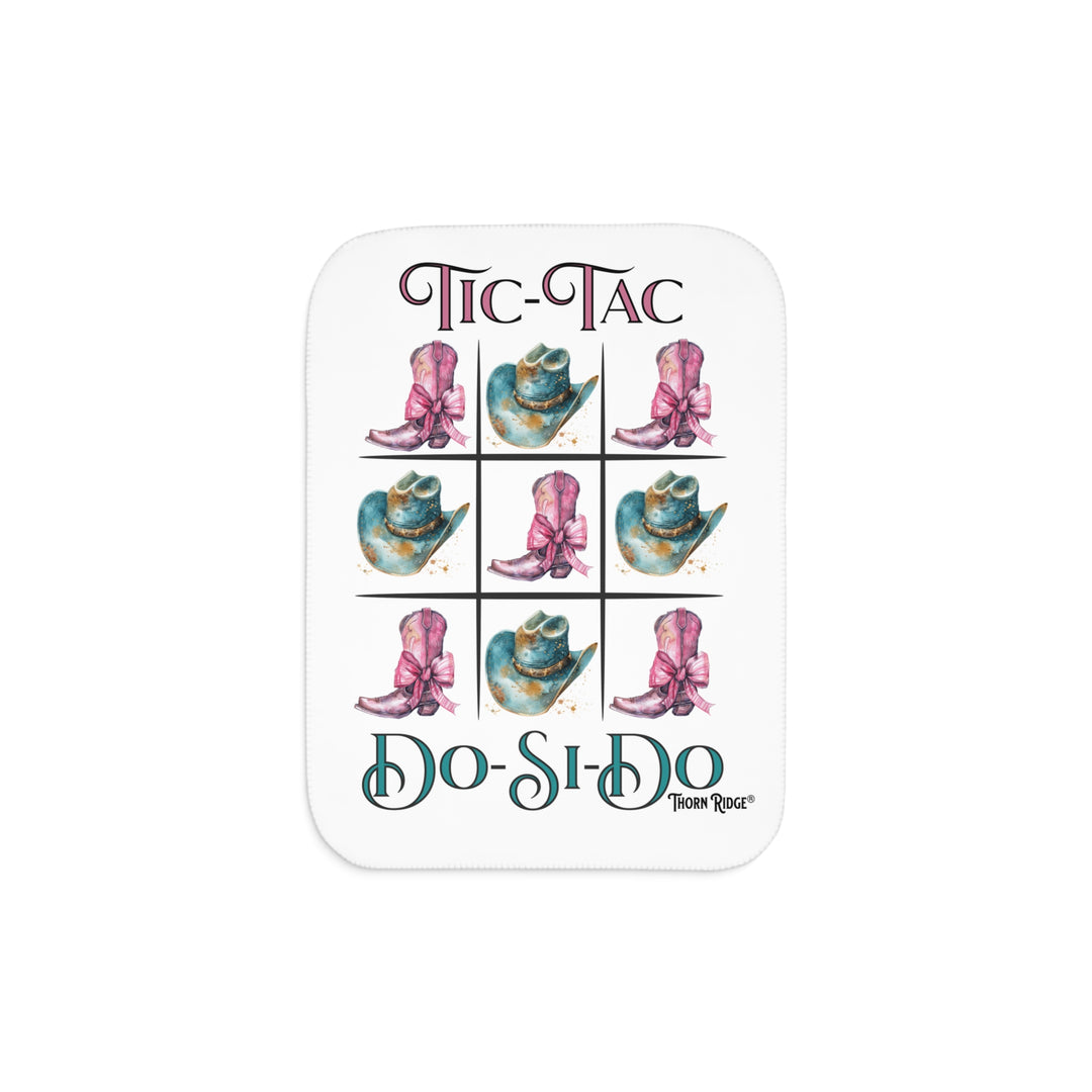 White Sherpa Blanket with a Tic-Tac Do-Si-Do image of a tic-tac-toe board with pink cowboy boots with a bow in the four corners and middle and blue cowboy hats on the sides by Thorn Ridge®