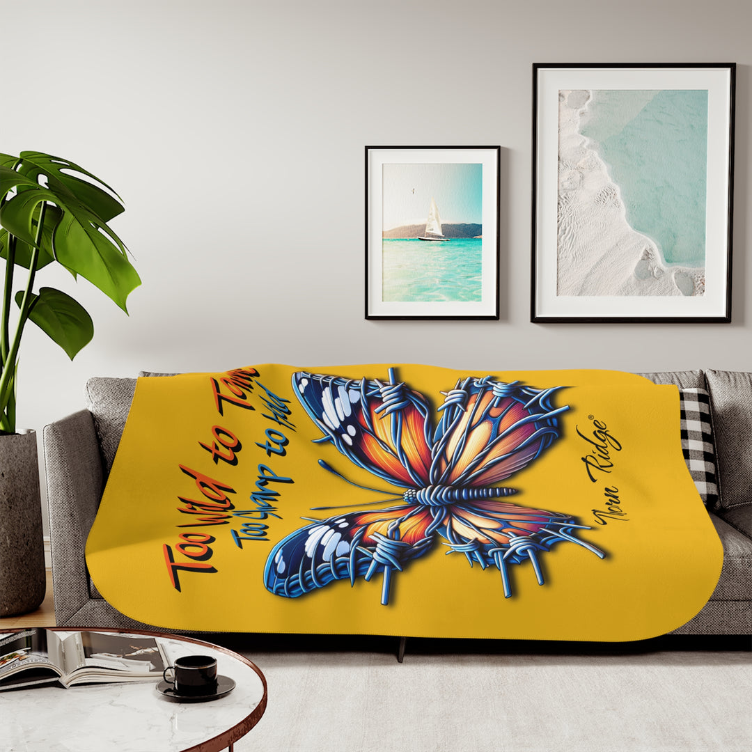 Butterfly design with barbed wire it's wings on a yellow sherpa blanket with text that says Too Wild to Tame Too Sharp to Hold and is the Barbfly legend from Thorn Ridge®