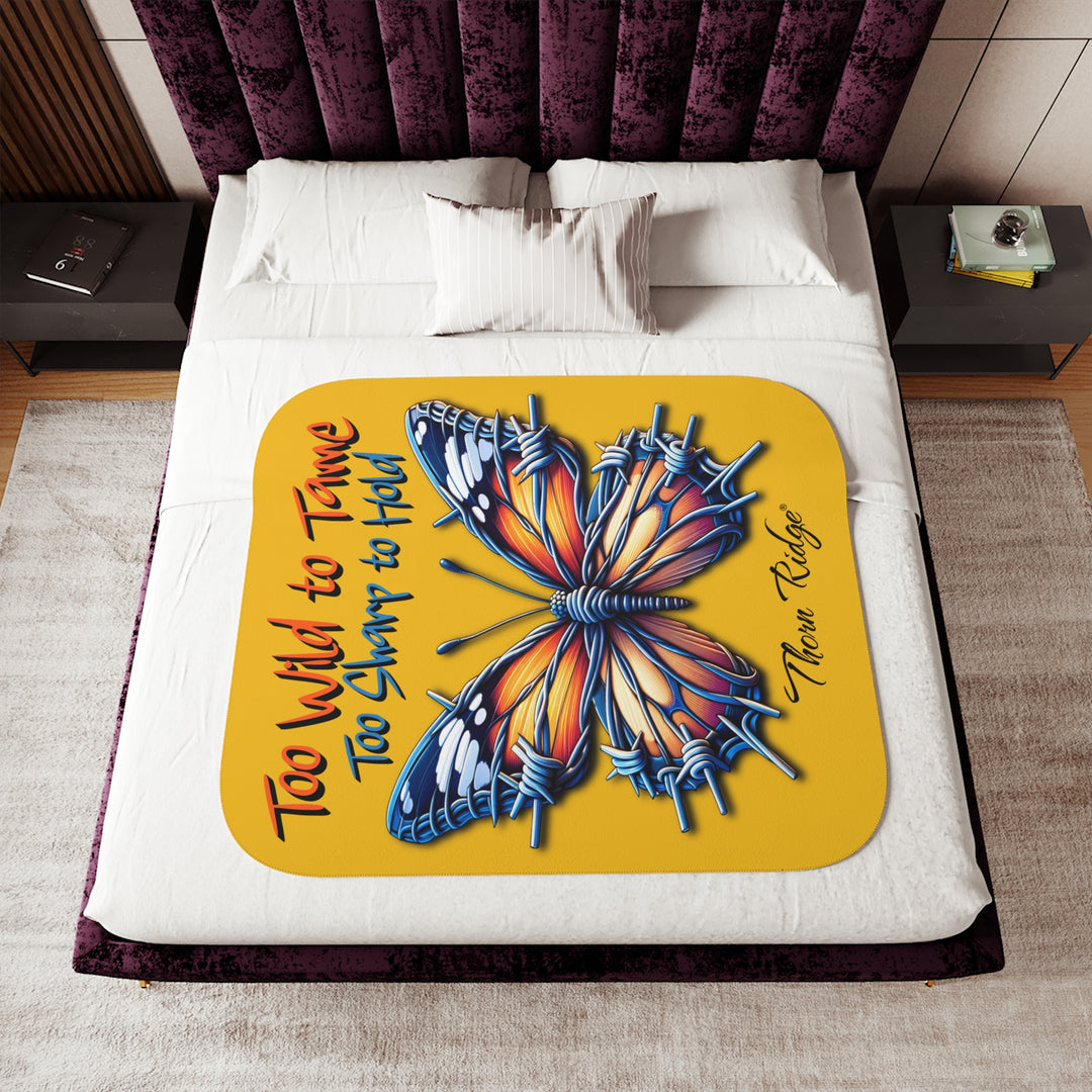 Butterfly design with barbed wire it's wings on a yellow sherpa blanket with text that says Too Wild to Tame Too Sharp to Hold and is the Barbfly legend from Thorn Ridge®